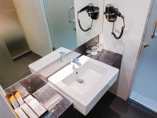 a bathroom with a white sink and a mirror at Brits Hotel Karawang in Karawang
