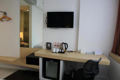 a room with a desk with a television and a chair at Brits Hotel Karawang in Karawang