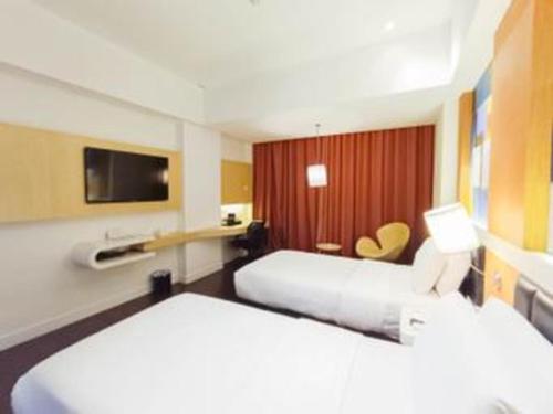 a hotel room with two beds and a tv at Brits Hotel Karawang in Karawang