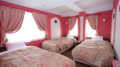 two beds in a room with red walls and windows at Arabian Art Hotel & Gallery in Onjuku