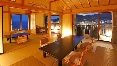 a living room with a table and chairs with a view at Tsukino Sumika Atami Juraku Hotel in Atami