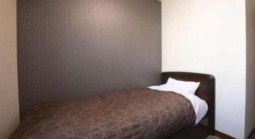 a bed in a corner of a room at Business Hotel Wako in Ichinomiya