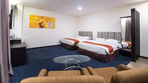 a hotel room with two beds and a couch at Aston Boutec Hotel Lintas Plaza in Kampong Nasob