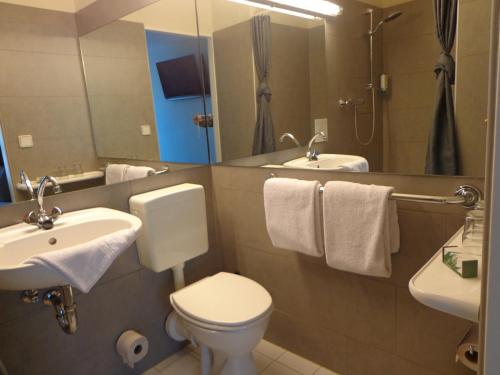 a bathroom with a toilet and a sink and a mirror at Hotel am Wall in Soest