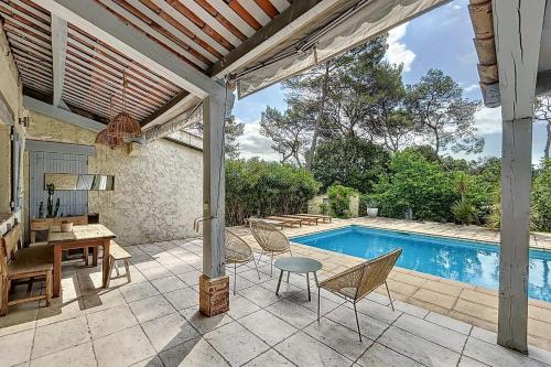 un patio avec une table et des chaises et une piscine dans l'établissement Mougins Charming villa with swimming pool 3 bedrooms in the pine forest, à Mougins