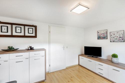 a living room with white cabinets and a flat screen tv at Ferienhaus Weitblick in Eslohe