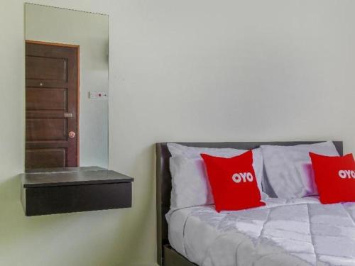 a bedroom with a bed with red pillows and a mirror at OYO 822 Zande Motel Kuala Selangor in Kuala Selangor