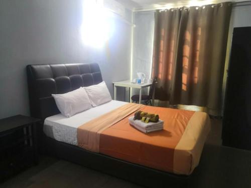 a bedroom with a large bed with an orange blanket at OYO 90473 Opah Inn Hotel in Jertih