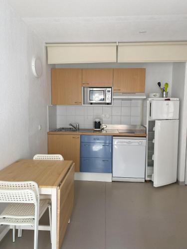 une cuisine avec une table et un réfrigérateur blanc dans l'établissement APARTAMENTO GEORGE V T2 plus Alcôbe, à Cauterets