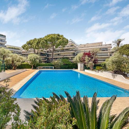 une piscine en face d'un grand bâtiment dans l'établissement Joli studio 4 pers piscine tout confort, à Juan-les-Pins