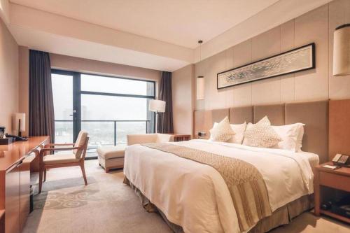 a hotel room with a large bed and a desk at Suzhou Qingshan Conference Center in Suzhou
