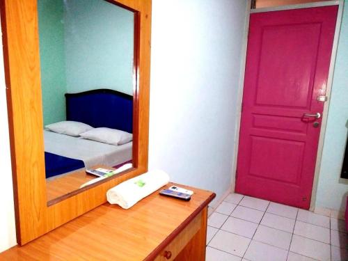 a bedroom with a red door and a mirror at Wisma Jampea in Makassar