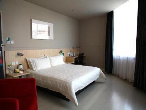 une chambre avec un lit blanc et une chaise rouge dans l'établissement Jinjiang Inn Yichun Water Park Branch, à Shuangzihe