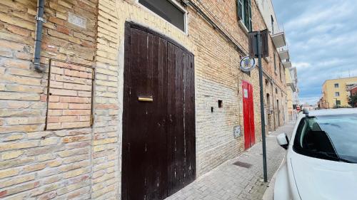 eine schwarze Tür an der Seite eines Backsteingebäudes in der Unterkunft CentralStay Matera in Matera