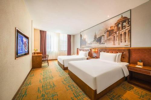 a hotel room with two beds and a painting on the wall at James Joyce Coffetel Chengdou Wuqing Wanda Plaza in Chengdu