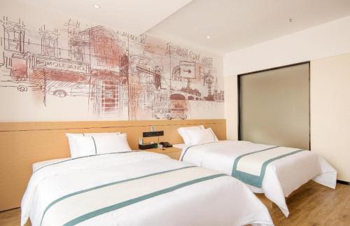 two beds in a room with drawings on the wall at City Comfort Inn Ji'an South Administrative Center in Ji'an