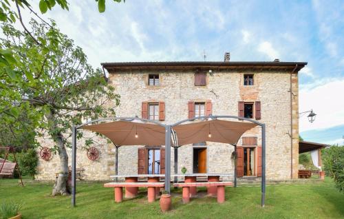 a stone house with two picnic tables in front of it at La Giuncaia in Pieve Santo Stefano