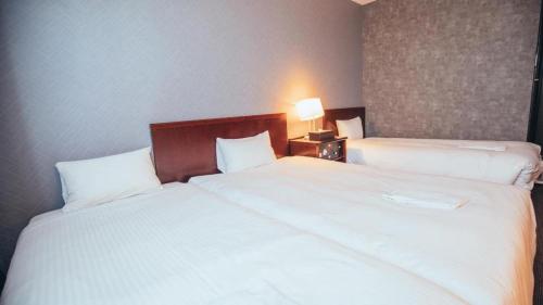 a hotel room with two beds and a lamp at Hotel Areaone Miyazaki in Miyazaki