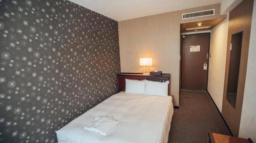 a hotel room with a bed and a wall at Hotel Areaone Miyazaki in Miyazaki