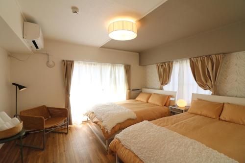 Un dormitorio con dos camas y una ventana. en Kandaminium Odori, en Ōdōri