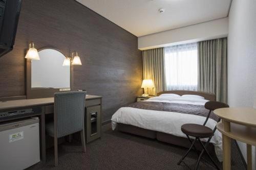 a hotel room with a bed and a desk at Sunroute Aomori Hotel in Aomori