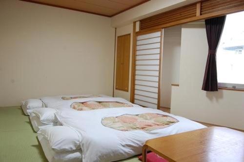 a room with three white beds in it at Sunroute Aomori Hotel in Aomori