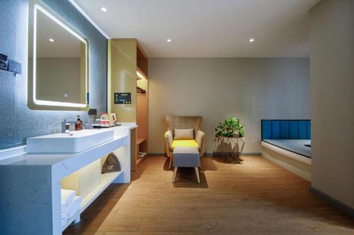 a bathroom with a sink and a chair and a bed at Magnotel Business Yangzhou China Grand Canal Museum Wanda Plaza in Yangzhou