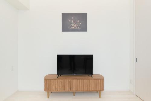 a television on a wooden stand in front of a white wall at Cure Skytree in Tokyo