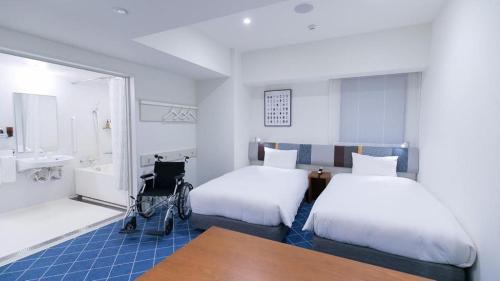 a room with two beds and a wheelchair in it at Hotel Edit Yokohama in Yokohama
