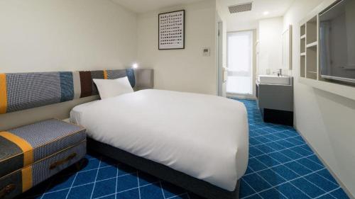 a bedroom with a large white bed and a sink at Hotel Edit Yokohama in Yokohama