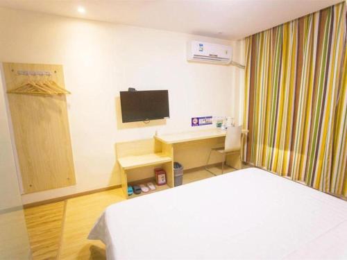 a room with a bed and a desk with a television at 7 Days Inn Yiyang Shengli Road in Shangrao