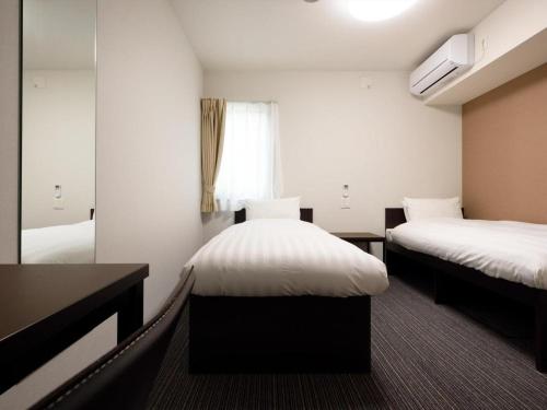 a hotel room with two beds and a mirror at La'gent Inn Kesennuma in Higashi-hachimammae