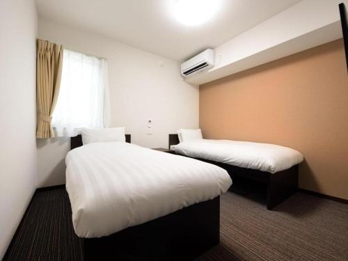 a hotel room with two beds and a window at La'gent Inn Kesennuma in Higashi-hachimammae