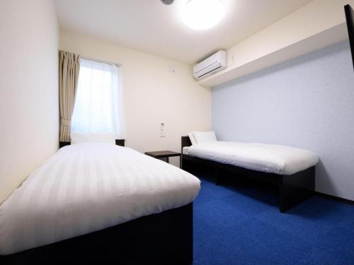 a hotel room with two beds and a window at La'gent Inn Kesennuma in Higashi-hachimammae