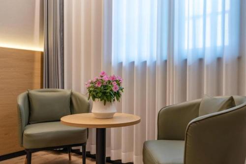 a room with two chairs and a table with flowers on it at GreenTree Inn Linxi International Convention Center Express Hotel in Linyi