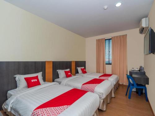 two beds in a room with red and white sheets at Capital O 89538 Ocean Hotel in Labuan
