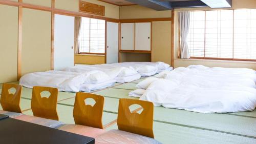 a room with four large beds with white sheets at Hotel AreaOne Banjinmisaki in Kashiwazaki