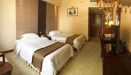 a hotel room with two beds and a television at Chaozhou Hotel in Chaozhou