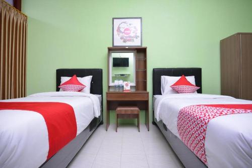 a bedroom with two beds and a table with a mirror at Super OYO 1046 Omah Pathok in Yogyakarta