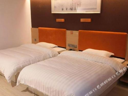 two beds in a hotel room with white sheets at 7 Days Premium Hotel Ji'an Taihe Gongnongbing Avenue in Ji'an