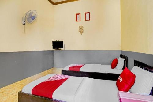 a bedroom with two beds with red and white sheets at OYO 90405 Penginapan Sasti Kuningan in Kuningan