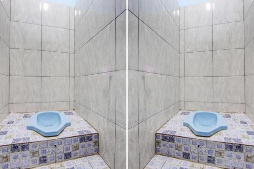a bathroom with a shower with a blue toilet at Hotel O Gioba Kost Syariah in Grobogan