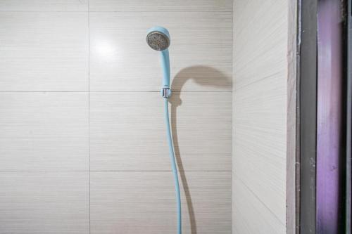 a shower with a blue shower head on a wall at OYO 94150 Gateway Apartment Pasteur By Eldian in Bandung