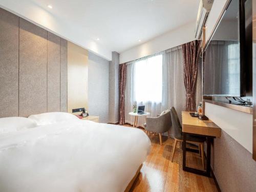 a hotel room with a bed and a desk and a window at Yimi Hotel Guangzhou Yuexiu Park North Branch in Guangzhou