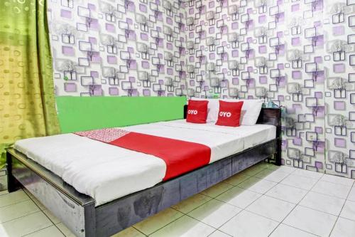 a bedroom with a bed with two red pillows at OYO 92759 Penginapan Piji Kembar in Tawangmangu