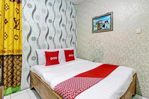 a bedroom with a bed with two red pillows at OYO 92759 Penginapan Piji Kembar in Tawangmangu