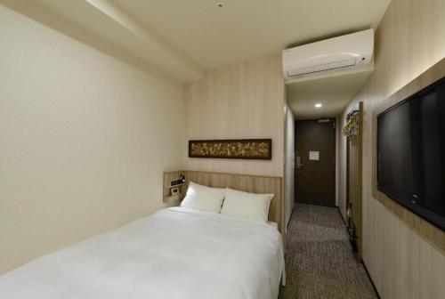 a bedroom with a white bed and a flat screen tv at Hotel IL FIORE Kasai in Tokyo