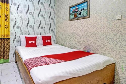 a bed with two red pillows in a room at OYO 92759 Penginapan Piji Kembar in Tawangmangu