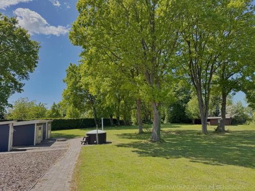 a park with trees and a bench and a building at Ferienhaus Nordprinz mit Sauna und Whirlpool in Geestland