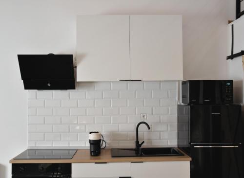 a kitchen with a sink and a black refrigerator at Miling Vendégház in Földes